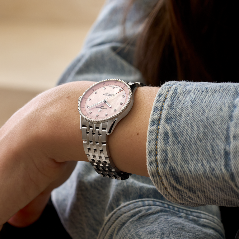 1x1_A77320D91K1A1_Navitimer_32_PinkSteel_WristShot_Ecom.png