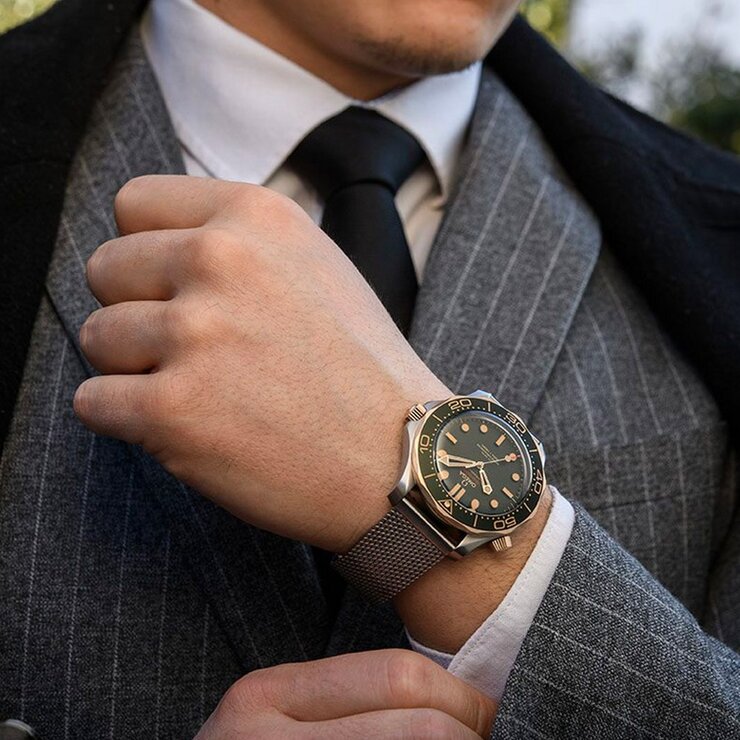 Omega horloge met een kast in bronsgoud 9kt op titanium, met een wijzerplaat in het groen en een diameter van 42 mm