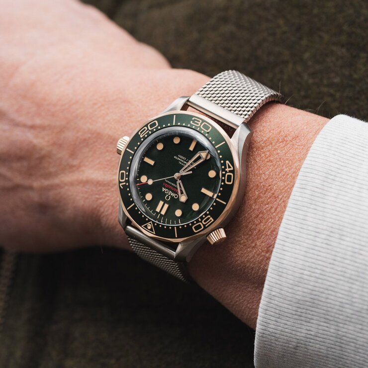 Omega horloge met een kast in bronsgoud 9kt op titanium, met een wijzerplaat in het groen en een diameter van 42
